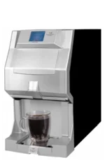 A silver automatic coffee machine dispenses coffee into a clear glass mug placed on its tray.