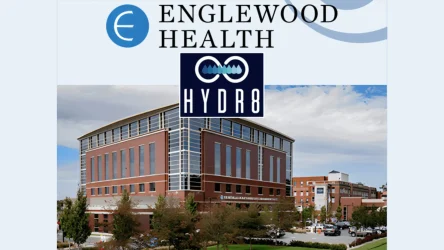 Englewood Health building exterior with HYDR8 logo displayed above the entrance, surrounded by trees and parked cars under a partly cloudy sky.