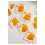 Several single-serve nacho cheese sauce packets and some spilled cheese are scattered on a white surface.